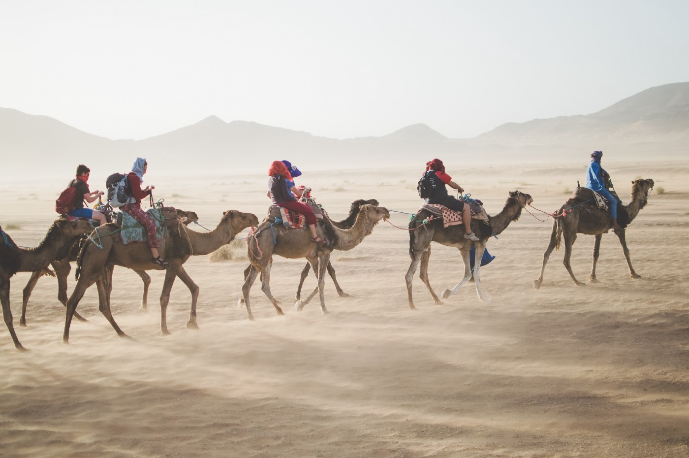 A family riding through the desert on camels